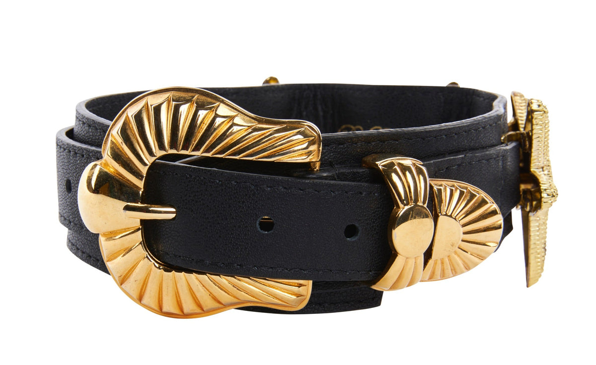 Black leather collar featuring a large, ridged gold buckle shaped like a stylized starfish and matching gold hardware accents.
