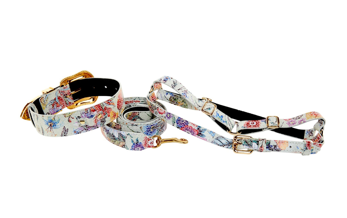 White leather collar, leash, and harness set featuring a colorful floral mosaic pattern with gold-tone hardware and Swarovski crystal accents, displayed on a white background.