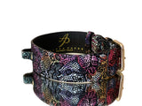 Black leather pet collar with colorful floral lace pattern and gold-toned classic buckle hardware, shown with a reflective surface underneath.