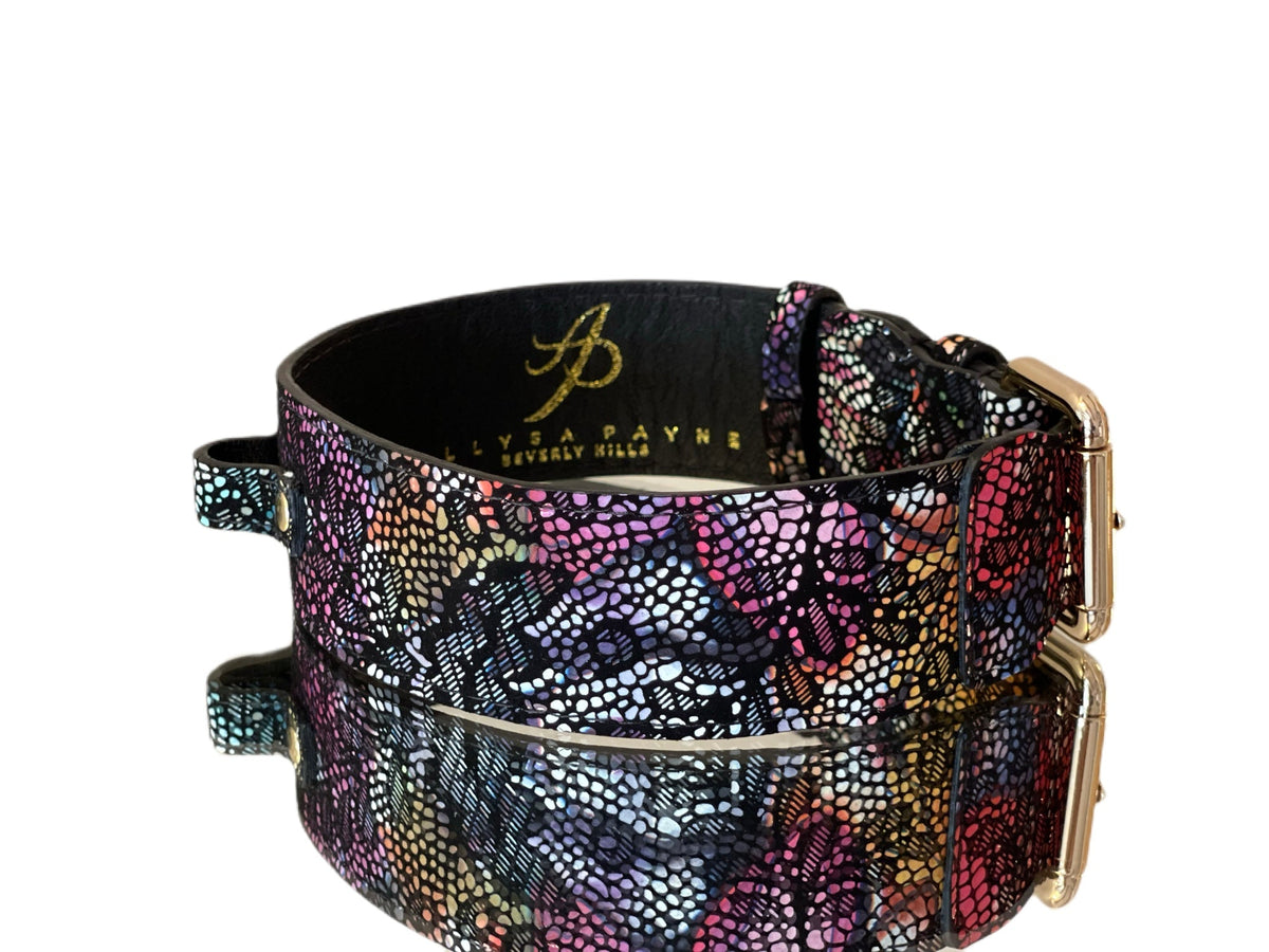 Black leather pet collar with colorful floral lace pattern and gold-toned classic buckle hardware, shown with a reflective surface underneath.