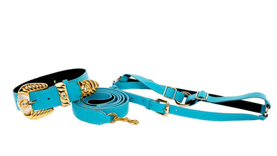 Aqua blue Italian leather pet collar, leash, and harness set with ornate Swarovski crystal detailing displayed on a beige surface