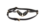 Black vegan leather harness with gold hardware displayed on a dark surface