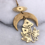 Magic Mushroom Ornament hanging against a plain wall showing its brass form
