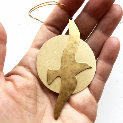 Into the Sun Ornament hand-cut and hammered brass wall hanging on cream fabric background