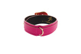 Wide fuchsia Italian leather collar with a textured pattern, featuring custom gold-toned western floral hardware and a silver D-ring, shown in a circular shape.