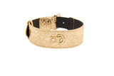 Wide gold floral-embossed leather dog collar with classic gold hardware and a small attached D-ring on black inner lining.