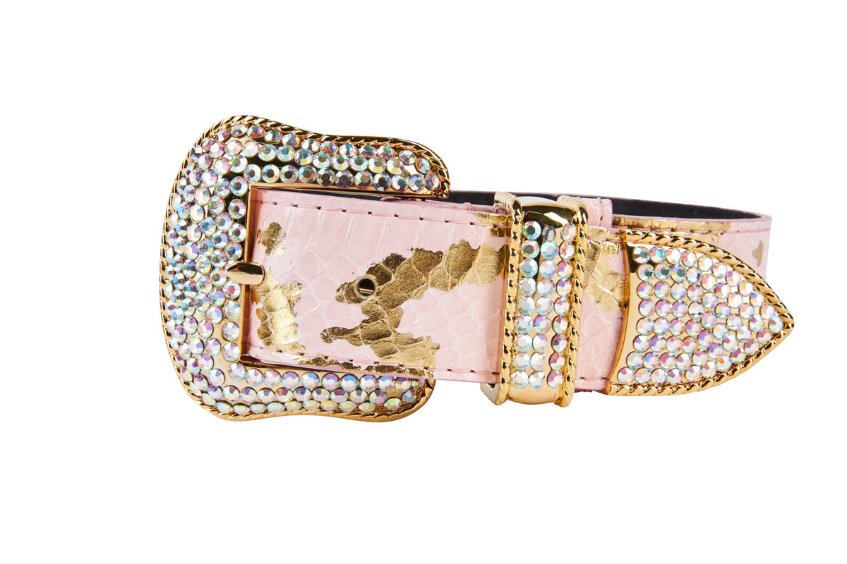 Soft pink snake-patterned collar with metallic gold accents and a large gold buckle encrusted with iridescent Swarovski crystals, shown against white background.