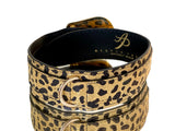 Leopard print Italian leather pet collar with gold-tone D-ring and black interior lining, shown in a rolled position highlighting pattern detail.
