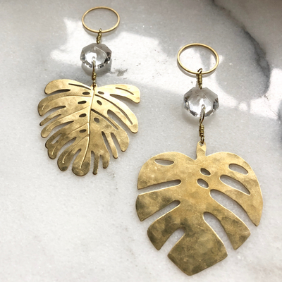 Mini Mini Monstera Suncatcher made of brass sheet with vintage glass crystal hanging against a white wall