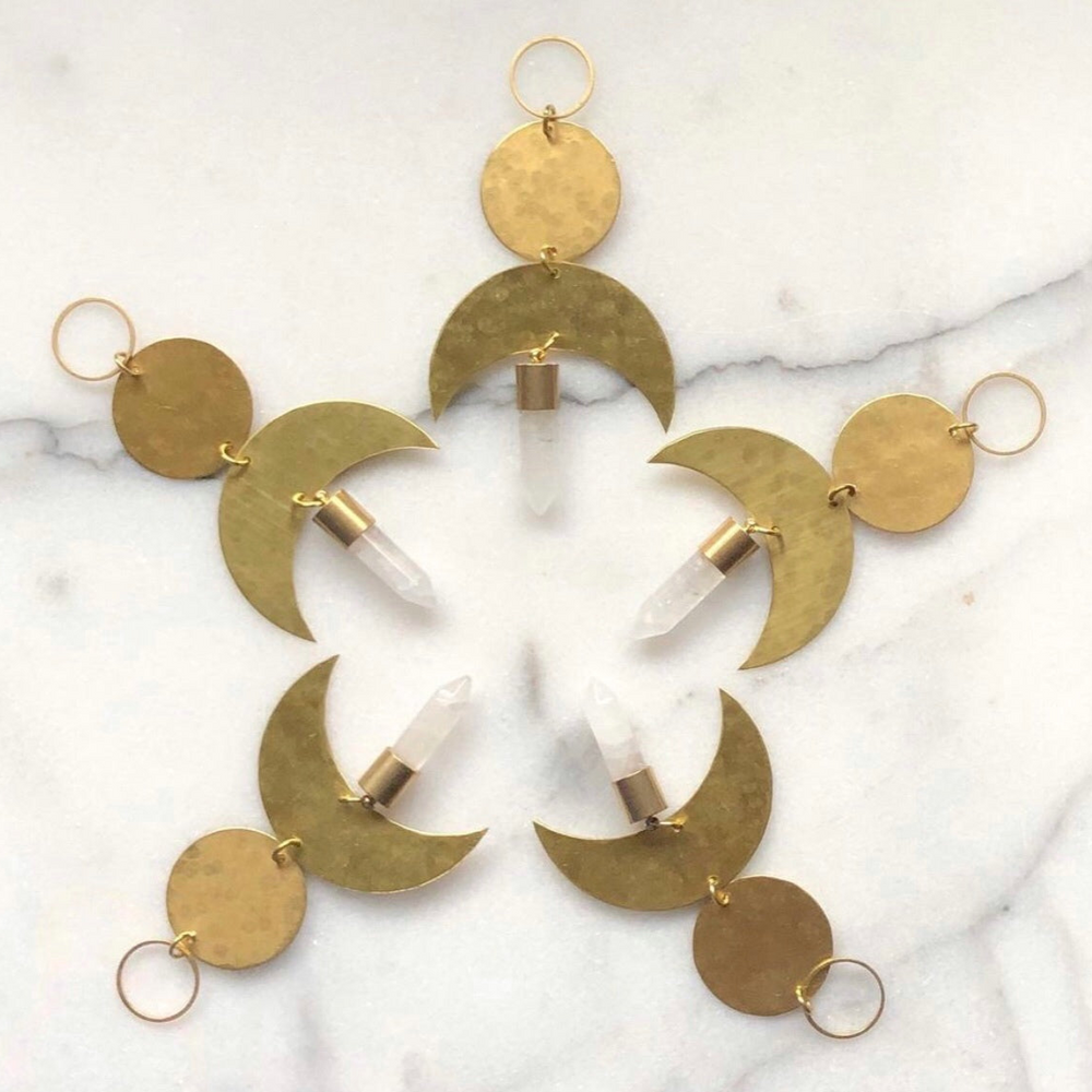 Moon Drop Ornament With Quartz Crystal by Vida + Luz, brass crescent moon with clear quartz crystal point hanging indoors