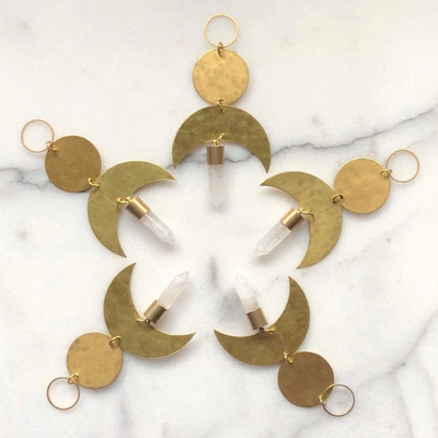 Moon Drop Ornament With Quartz Crystal by Vida + Luz, brass crescent moon with clear quartz crystal point hanging indoors