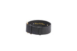 Black wide leather collar with gold-tone buckle and two gold rivets, featuring subtle gold script inside the band, shown on a white background.