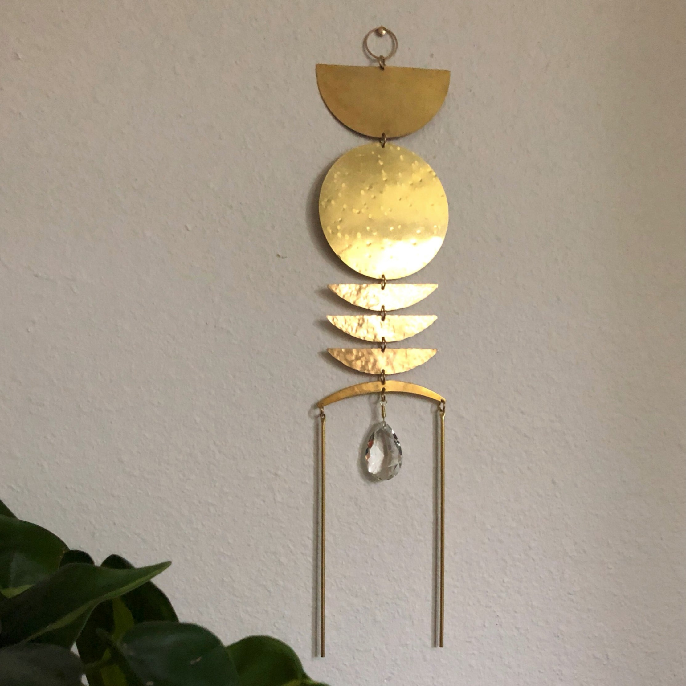 Break of Dawn Sun Catcher hanging indoors, showing brass and faceted crystal details