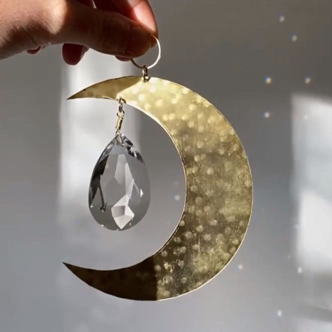 Artemis Suncatcher by Vida + Luz showing brushed brass sheet and vintage faceted crystal in sunlight