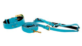Aqua blue Italian leather dog collar, leash, and harness set with gold hardware and black lining, displayed on a white background.