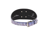 Close-up of a purple and silver iridescent snake-print collar with a metallic buckle and D-ring, featuring a smooth black inner lining with logos.