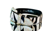 Italian leather pet collar with tiger print hair-on-hide pattern, featuring a buckle and bow-shaped hardware encrusted with Swarovski crystals, shown on a reflective surface.