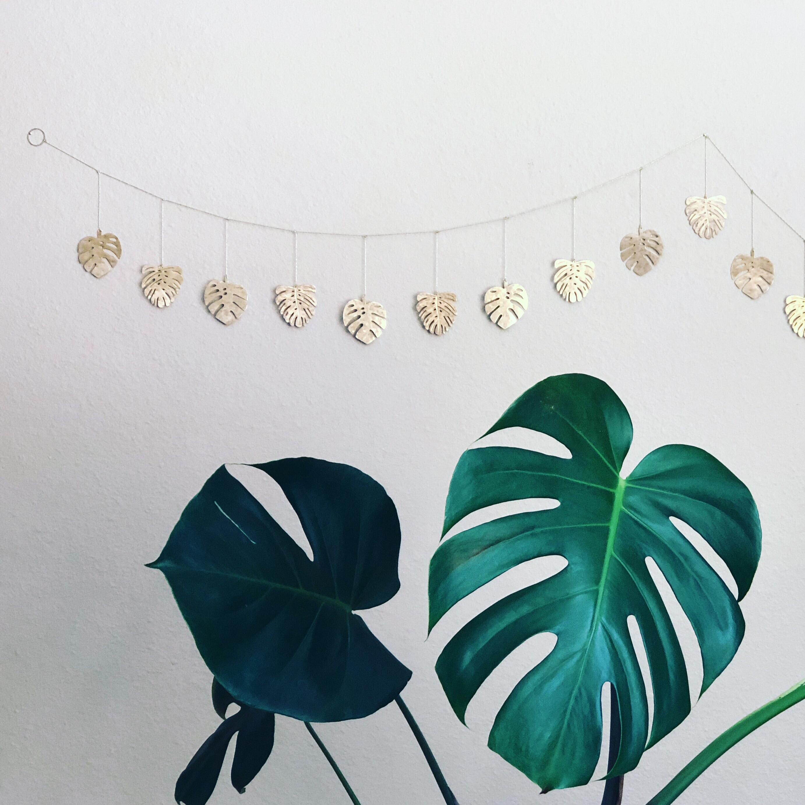 Close-up image of Monstera Hammered Brass Garland with hammered brass monstera leaf shapes