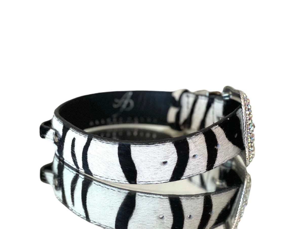 Black and white tiger print hair-on-hide leather pet collar with sparkling Swarovski crystal buckle, shown with reflective surface underneath and white background.