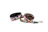 Classic collar and leash set featuring multicolored floral, skull, and snake print on Italian leather, shown coiled and fastened with silver hardware.