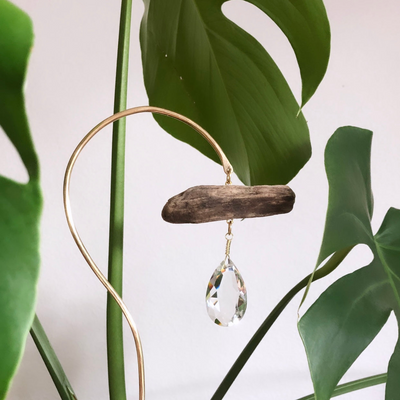 Planty Suncatcher Stick composed of driftwood and brass wire holding a vintage glass crystal catching sunlight