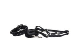 Black leather belt with adjustable metal buckle next to a matching leash featuring a metal clasp and an adjustable harness with silver hardware.