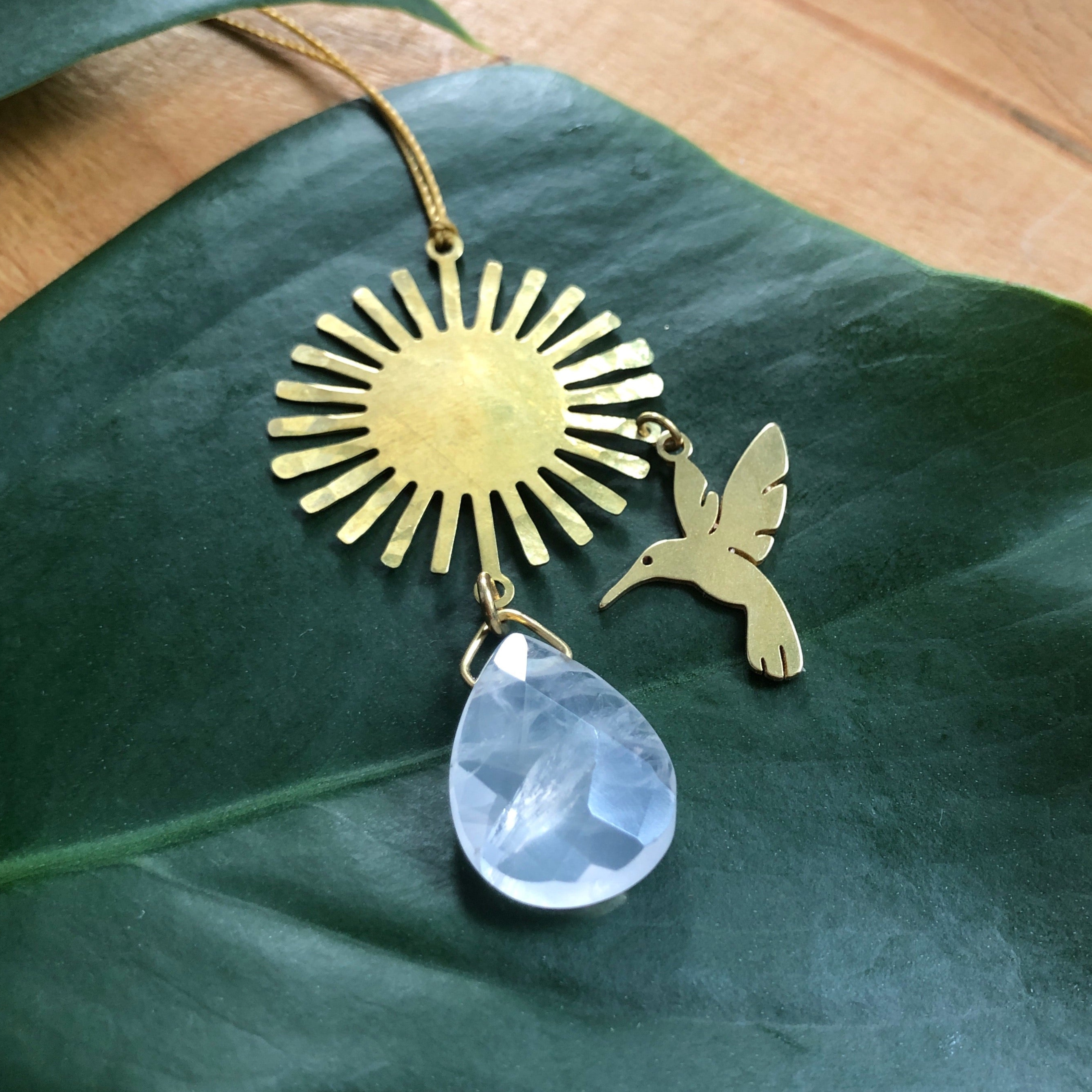 Picaflor flower kisser ornament with rose quartz hanging against a neutral background