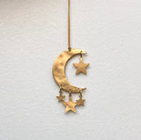 Brass crescent moon ornament with four small attached star charms, hanging on a thin golden string against a white background.