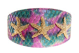 Curved wide collar with iridescent purple and teal tilapia scale pattern, adorned with three textured gold starfish evenly spaced across its surface.