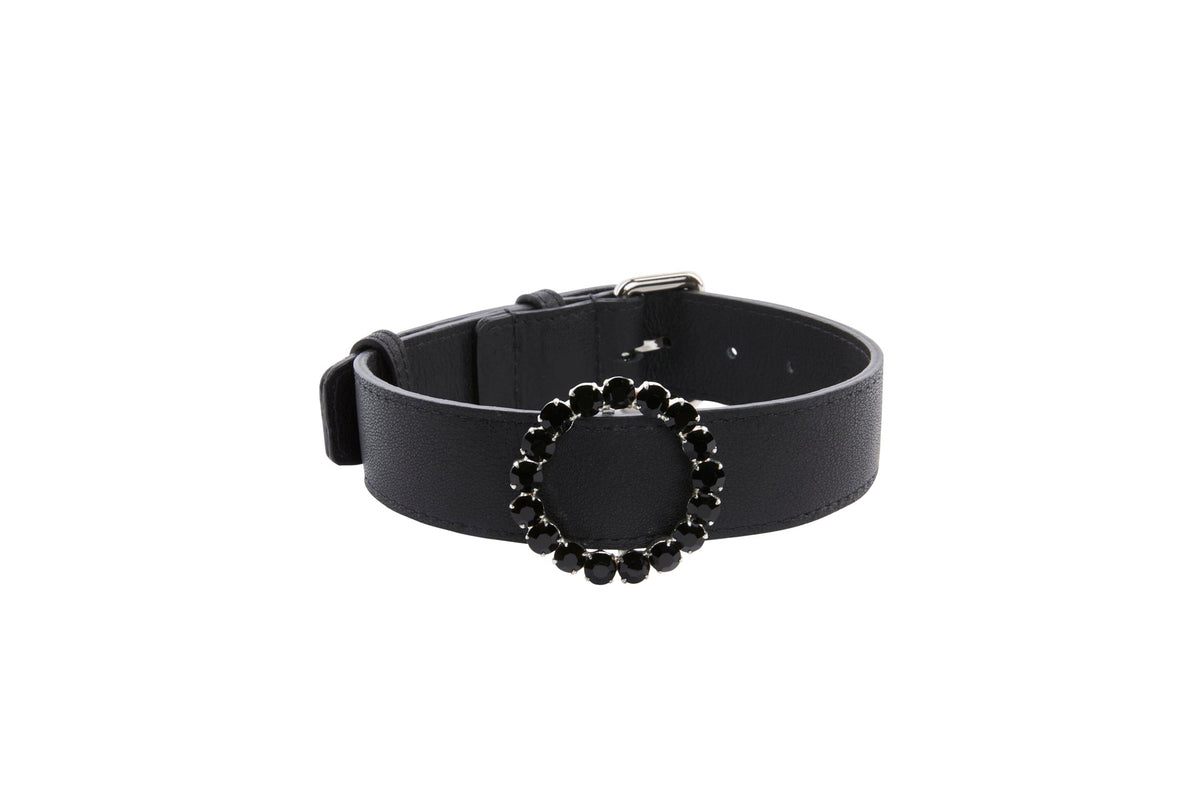 Black leather collar featuring a circular ring adorned with black crystals, shown against a white background from a slight side angle.