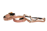 Set of three pink embossed snake-patterned leather collars and harnesses with gold-tone Swarovski crystal buckle details, laid out on white background.
