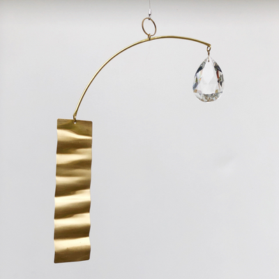Daydream Suncatcher by Vida + Luz showing brass sheet with glass crystal accents hanging indoors