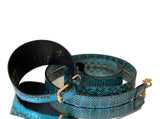 Turquoise and black snakeskin patterned pet collar and leash set with gold-tone metal buckle and clasp, arranged coiled on a white background.
