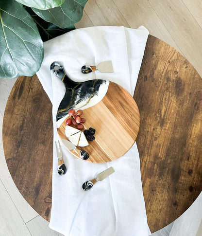 Wooden Cheese Paddle Acacia Serving Charcuterie Board with cheese and fruits on a round wooden table.