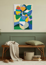 Abstract floral painting with overlapping shapes in blue, green, yellow, pink, and orange hues framed on a light beige wall above a wooden bench with green cushion and cream throw.