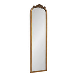 Tall rectangular mirror with an arched top and a carved floral crest in a warm brown wooden frame against a white background.