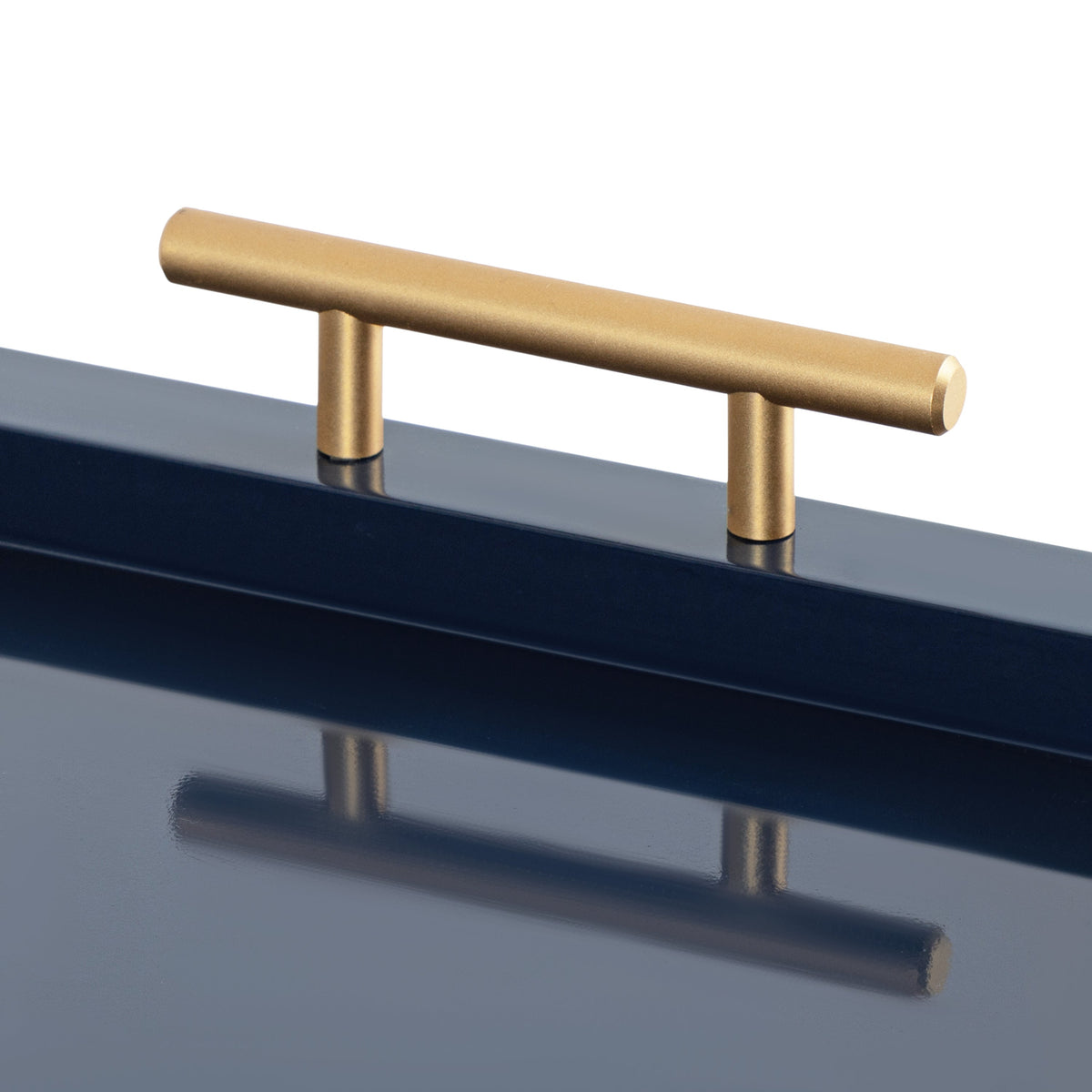 Close-up of a minimalistic gold tubular handle attached to a glossy deep navy blue surface, reflecting the handle below.