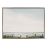 Framed canvas print showing a pale blue sky over a calm ocean beach with grassy dunes and a rope fence in the foreground.