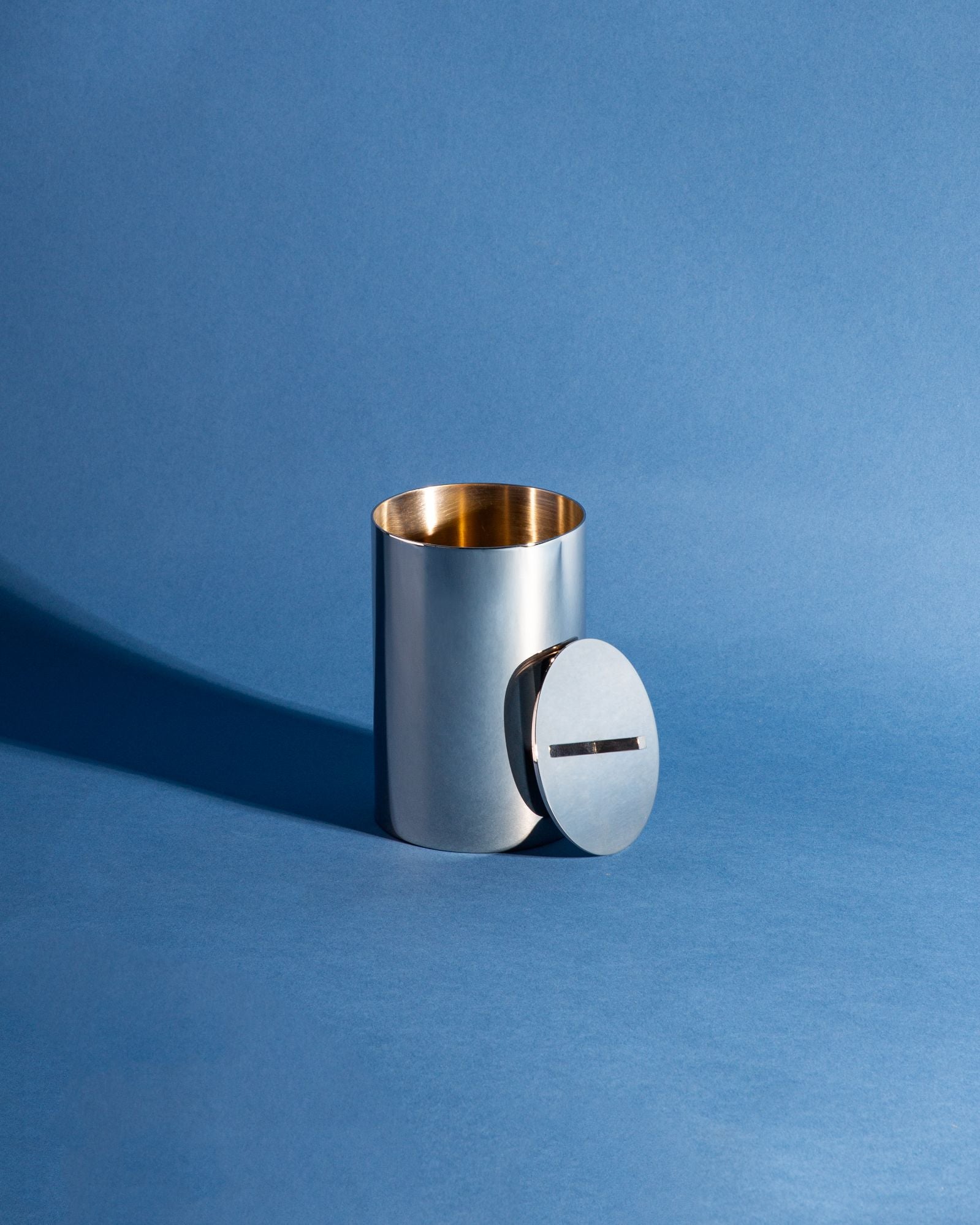 Josef Canister in polished brass showing round canister, rectangular stem, and matching lid