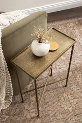 Slim rectangular metal side table with a textured gold-toned top and slender legs, holding a round white vase with dried flowers and a small round wooden dish.