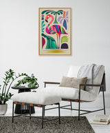 Colorful mid-century modern style flamingo artwork with geometric shapes and tropical leaves, framed and hanging above a white cushioned lounge chair with a matching ottoman in a minimal room.