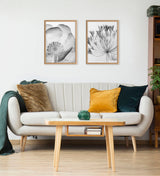 Minimalist living room with a light gray sofa adorned with mustard, teal, and brown pillows, a wooden coffee table with a green geometric decor piece, and two black-and-white floral x-ray prints framed above.