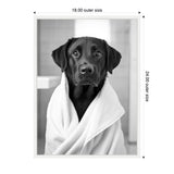 Black Labrador retriever wrapped in a white towel, looking directly at the camera with a neutral background and tiled wall behind.