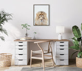 Modern wooden desk with white drawer units, a woven chair, and a white lamp, under a framed close-up portrait of a lion with a beige mane.
