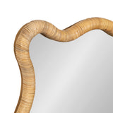 Close-up of a scalloped mirror corner framed with curved natural rattan weaving in a light tan color.