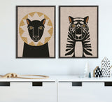 Framed canvas art of stylized animal faces: a black lion with a gold geometric mane and a black and beige tiger with gold eyes, both on neutral linen backgrounds.