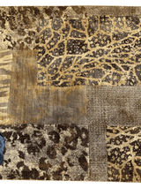 Section of a Karastan Carmel Santa Lucia Chestnut area rug featuring abstract and animal print patterns in brown, beige, and gold tones with textured weave variations.