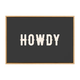 Black rectangular canvas with the word 'HOWDY' in large, cream-colored, stylized block letters framed in a natural wood frame.