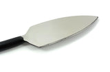 Close-up of a stainless steel cheese knife with a wide triangular blade and a black, curved handle against a white background.