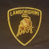 Yellow neon Lamborghini logo shield with stylized bull and uppercase text, illuminated against a dark background.